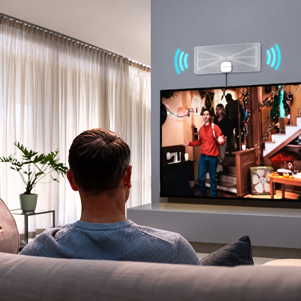 Man watching free HDTV with the Ultra-Vizion antenna mounted above the TV
